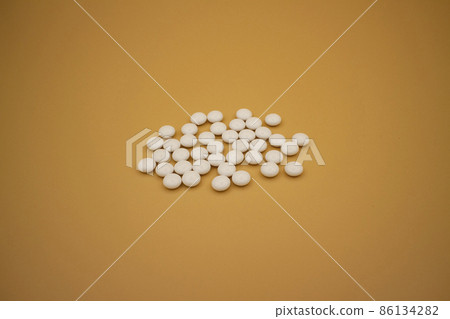 Spilled white round tablets / beige background medical white tablets on beige Spilled white round tablets / beige background medical white tablets on beige 86134282
