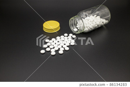 黑紙上的白藥片從藥瓶中溢出 黑紙上的白藥片從藥瓶中溢出 86134283