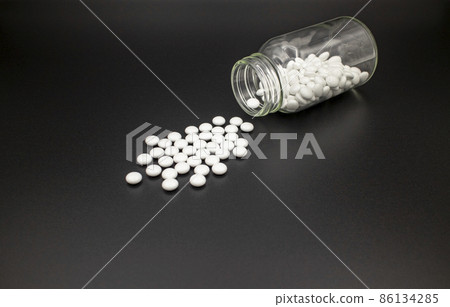黑紙上的白藥片從藥瓶中溢出 黑紙上的白藥片從藥瓶中溢出 86134285