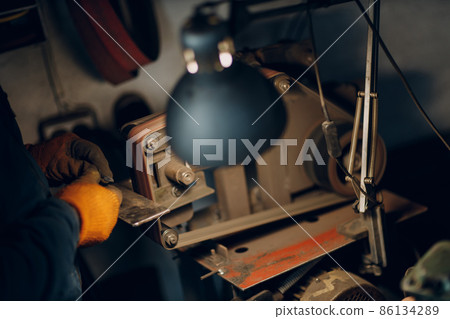 Blacksmith forges and sharpens arrow metal detail with hammer and anvil at forge. 86134289