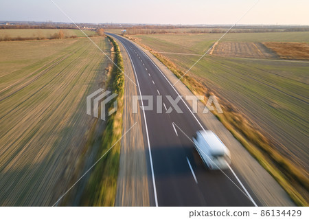 Aerial view of blurred fast moving cargo van driving on highway hauling goods. Delivery transportation and logistics concept 86134429