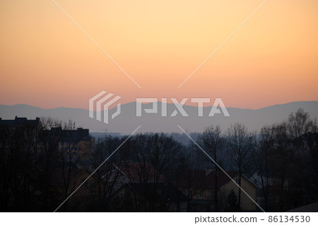 Beautiful evening panoramic landscape with bright setting sun over distant mountain peaks at sunset 86134530