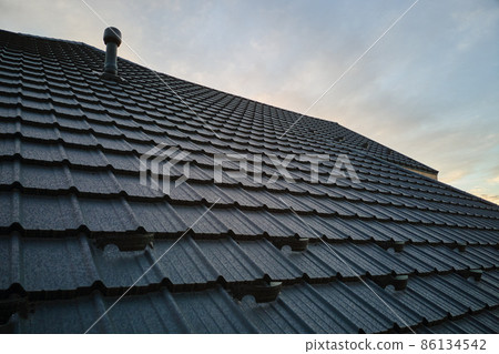 Snow guard for safety in winter on house roof top covered with steel shingles. Tiled covering of building Snow guard for safety in winter on house roof top covered with steel shingles. Tiled covering of building 86134542