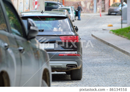 City traffic with cars parked in line on street side. 86134558