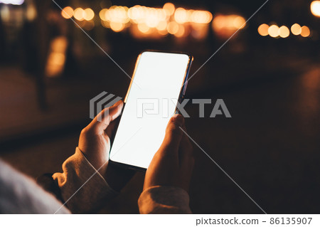 Smartphone with blank display in female hands outdoors Smartphone with blank display in female hands outdoors 86135907