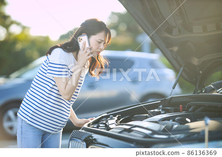 Young woman calling due to car breakdown 86136369