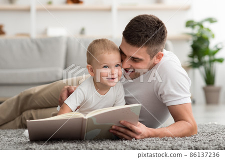 Portrait Of Caring Young Dad Reading Book To Happy Baby At Home 86137236