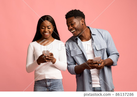 Cheerful african american couple using their newest cellphones Cheerful african american couple using their newest cellphones 86137286
