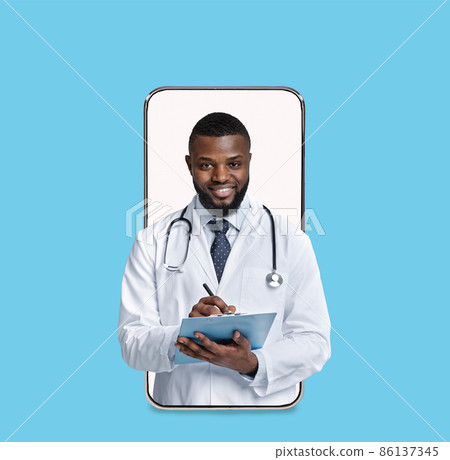 Smiling millennial african american male doctor in white coat make notes on blank screen of big phone Smiling millennial african american male doctor in white coat make notes on blank screen of big phone 86137345