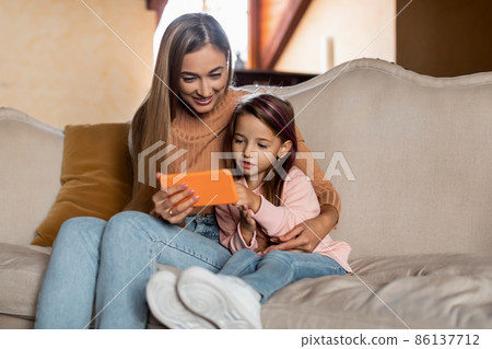 Portrait of smiling mom and girl using smartphone at home 86137712