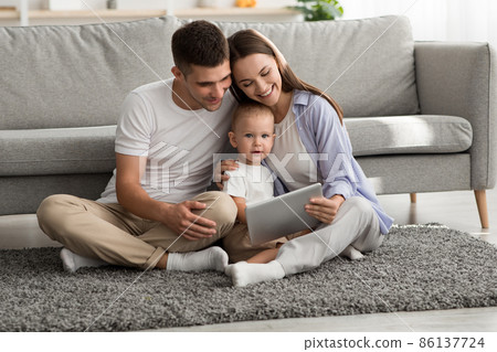 Happy Young Family Of Three With Infant Son Relaxing With Digital Tablet 86137724