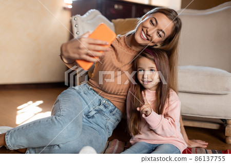 Portrait of smiling mom and daughter taking selfie using smartphone Portrait of smiling mom and daughter taking selfie using smartphone 86137755