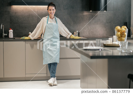 Young woman in apron and gloves in the kitchen 86137779