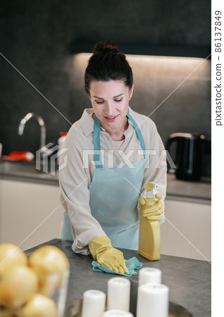A woman in apron cleaning the table in the kitchen 86137849