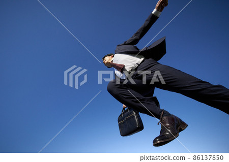 A man in a suit running in the blue sky 86137850