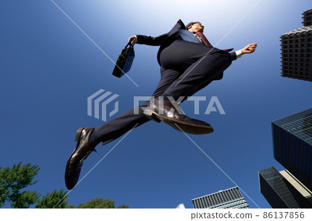 A business person in a suit running in the blue sky 86137856