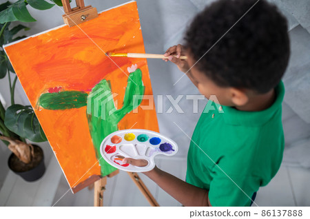 Top view of boy with palette painting on easel 86137888
