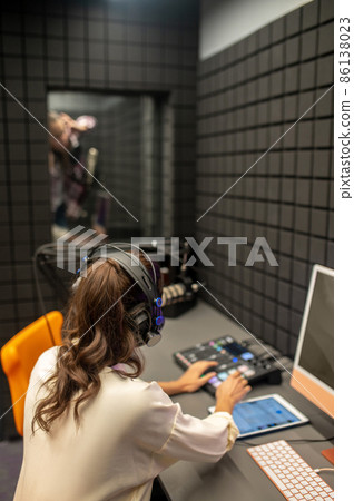 Professional female sound engineer monitoring the audio quality Professional female sound engineer monitoring the audio quality 86138023