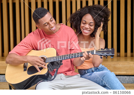 Man playing guitar and woman watching 86138066