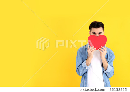 Attractive guy with heart on yellow background Attractive guy with heart on yellow background 86138235