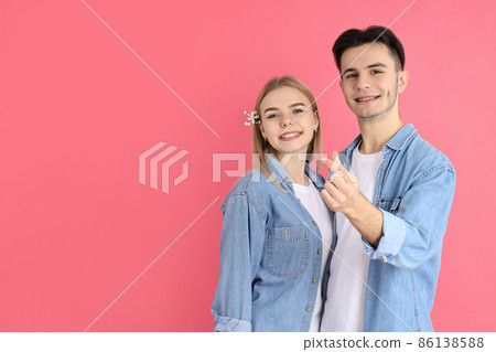 Cute couple with finger heart on pink background Cute couple with finger heart on pink background 86138588
