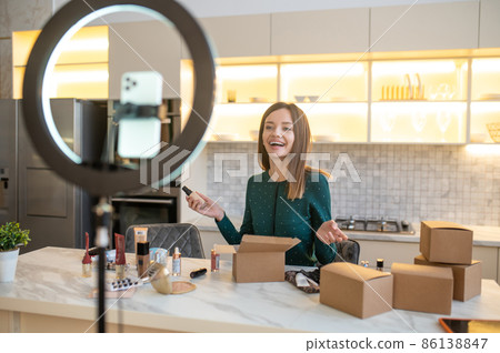Young woman in green dress conducting online cosmetic sale Young woman in green dress conducting online cosmetic sale 86138847