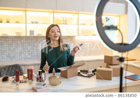 Young woman in green dress conducting online cosmetic sale Young woman in green dress conducting online cosmetic sale 86138850