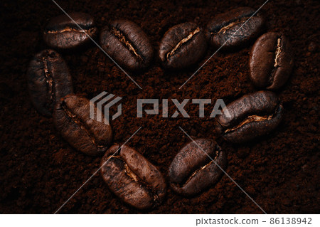 Kind of heart-shaped coffee beans lie on ground coffee. View from above. Flat lei. Love for coffee Kind of heart-shaped coffee beans lie on ground coffee. View from above. Flat lei. Love for coffee 86138942
