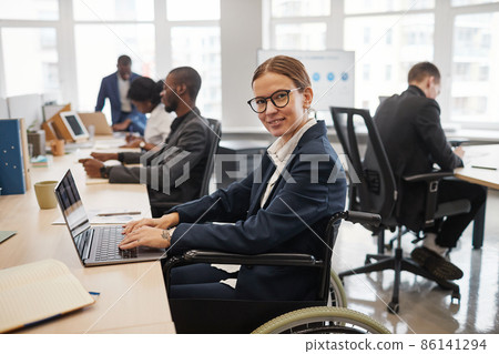 Smiling Woman in Wheelchair Working in Office 86141294