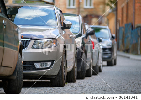 City traffic with cars parked in line on street side. City traffic with cars parked in line on street side. 86141341
