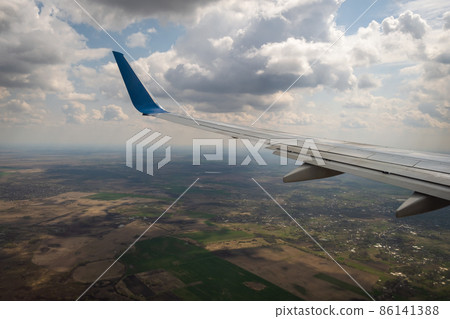 View of jet airplane wing landing at airport in bad weather. Travel and air transportation concept. 86141388