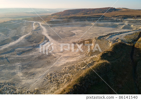 Aerial view of open pit mining site of limestone materials for construction industry with excavators and dump trucks Aerial view of open pit mining site of limestone materials for construction industry with excavators and dump trucks 86141540