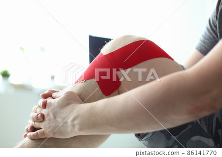 Therapeutic treatment of leg with red physio tape Therapeutic treatment of leg with red physio tape 86141770