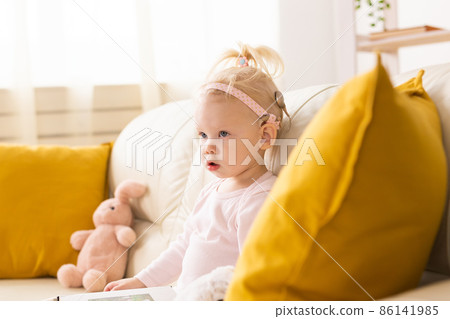 Child with cochlear implants sits on couch at home. Deafness and medical technology concept. 86141985