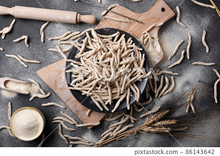 Whole grain wheat apulian pasta called Pizzarieddi or maccaruni on black table. Italian homemade pasta background, above 86143642
