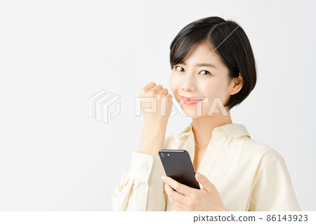 A young business woman operating a smartphone in front of a white background 86143923