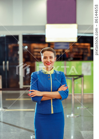 Joyful woman air hostess standing in airport terminal Joyful woman air hostess standing in airport terminal 86144658