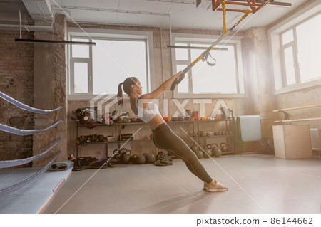 Athletic slender woman holding stretching tape in the gym Athletic slender woman holding stretching tape in the gym 86144662