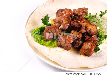 Pork shish kebab on lavash lies in a white plate on a white isolated background Pork shish kebab on lavash lies in a white plate on a white isolated background 86145538