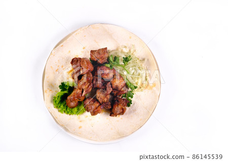 Pork shish kebab on lavash lies in a white plate on a white isolated background 86145539