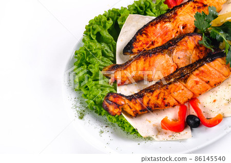 Fried fish with vegetables on a plate on a white isolated background Fried fish with vegetables on a plate on a white isolated background 86145540