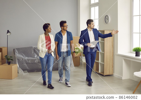 Realtor or real estate agent giving house tour to future buyers. Young black couple planning to buy new home. Boyfriend and girlfriend or husband and wife looking at modern, big, spacious apartment Realtor or real estate agent giving house tour to future buyers. Young black couple planning to buy new home. Boyfriend and girlfriend or husband and wife looking at modern, big, spacious apartment 86146002