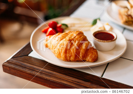 Golden croissant with strawberry marmalade and berries Golden croissant with strawberry marmalade and berries 86146702