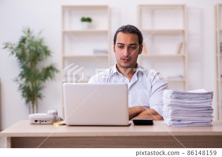 Young businessman employee unhappy with excessive work in the office Young businessman employee unhappy with excessive work in the office 86148159