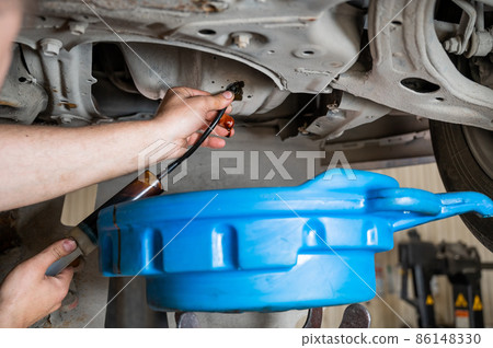Change of old oil in a car engine. Change of old oil in a car engine. 86148330