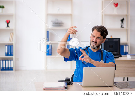 Young male doctor working in the clinic during pandemic 86148729