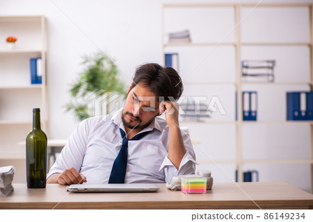Young alcohol addicted employee sitting in the office 86149234
