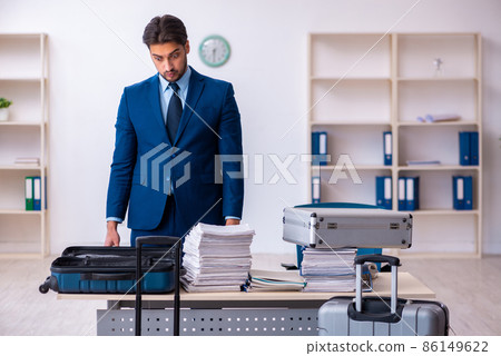 Young male employee preparing for business trip at workplace Young male employee preparing for business trip at workplace 86149622