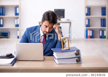 Young male employee in time management concept Young male employee in time management concept 86149636