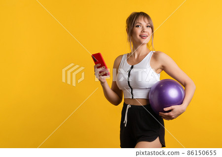 Sporty woman with pilates ball and phone 86150655